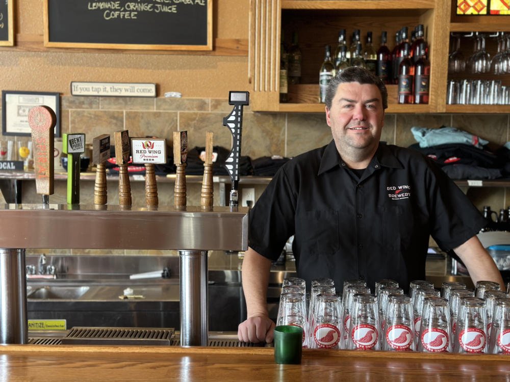 Norm standing behind the bar and smiling at the red wing brewery.